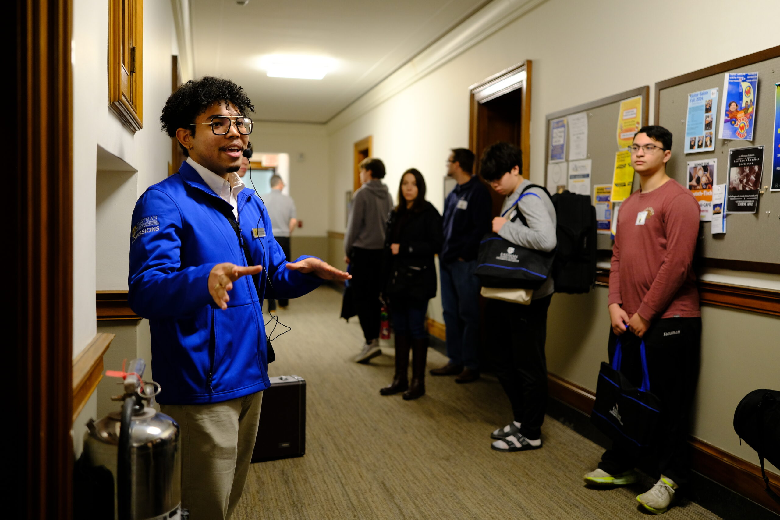 A student in a blue jacket leading a tour of Eastman campus inside Eastman's Main building