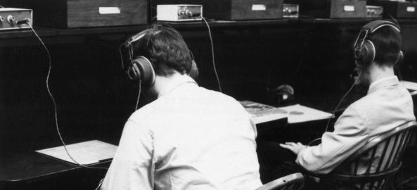 Two students wearing headphones seated at listening stations in the old Sibley Music Library (circa 1970s). Two students wearing headphones seated at listening stations in the old Sibley Music Library (circa 1970s).