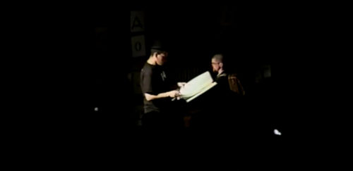 Part II at 32-15 performer holding open a codex to be read from