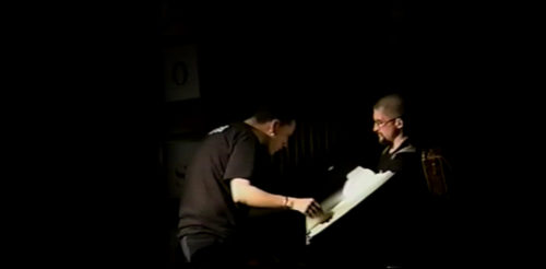 Part II at 32-21 performer holding open a codex to be read from