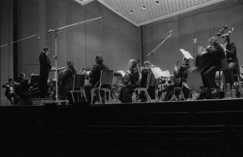 R1397-17 Eastman Philharmonia concert that featured the premiere of Krzystof Penderecki’s Partita for Harpsichord and Orchestra. At the conclusion of the Partita, Maestro Hendl invites the composer to the stage for bows. In the last shot, the composer, the soloist, and the conductor all join hands to acknowledge the applause.