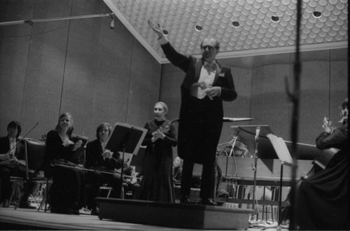 R1397-19 Eastman Philharmonia concert that featured the premiere of Krzystof Penderecki’s Partita for Harpsichord and Orchestra. At the conclusion of the Partita, Maestro Hendl invites the composer to the stage for bows. In the last shot, the composer, the soloist, and the conductor all join hands to acknowledge the applause.