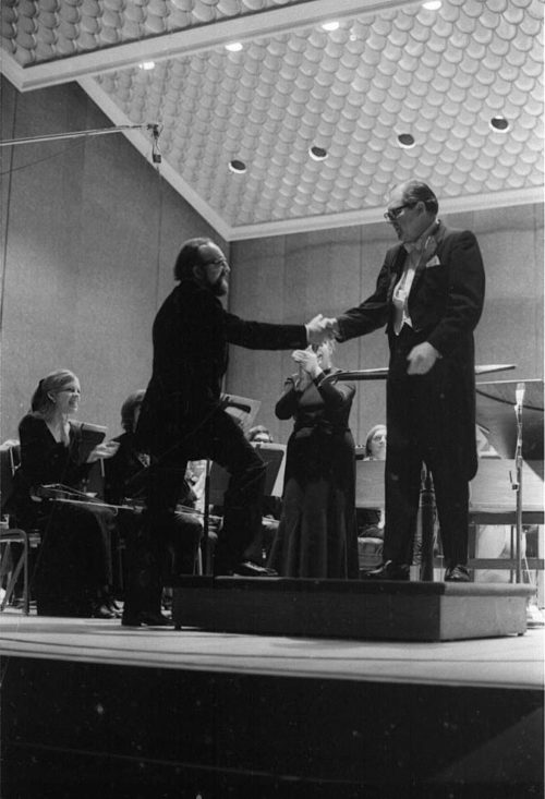 R1397-21 Eastman Philharmonia concert that featured the premiere of Krzystof Penderecki’s Partita for Harpsichord and Orchestra. At the conclusion of the Partita, Maestro Hendl invites the composer to the stage for bows. In the last shot, the composer, the soloist, and the conductor all join hands to acknowledge the applause.