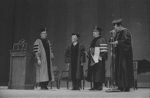 R1410-2 Conferral of an honorary doctoral degree on Shinichi Suzuki. Professor Donald Shetler hoods the newly named Dr. Suzuki; University President Robert Sproull stands at far left, and ESM Director Walter Hendl stands at far right.