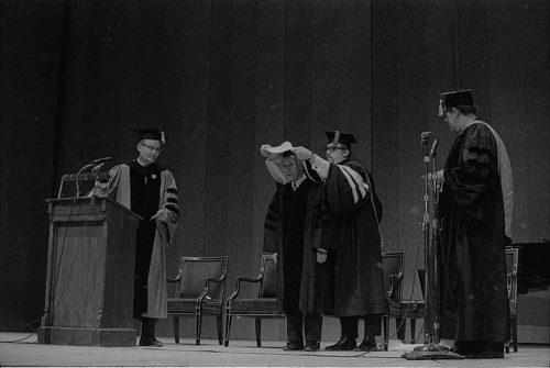 R1410-4 Conferral of an honorary doctoral degree on Shinichi Suzuki. Professor Donald Shetler hoods the newly named Dr. Suzuki; University President Robert Sproull stands at far left, and ESM Director Walter Hendl stands at far right.