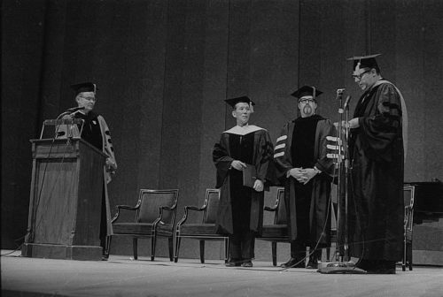 R1410-8 Conferral of an honorary doctoral degree on Shinichi Suzuki. Professor Donald Shetler hoods the newly named Dr. Suzuki; University President Robert Sproull stands at far left, and ESM Director Walter Hendl stands at far right.