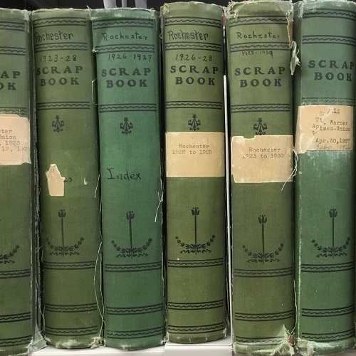 Sources from the ESM Archive The spines of six green, cloth-bound scrapbooks dating from the 1920s filed on a shelf.