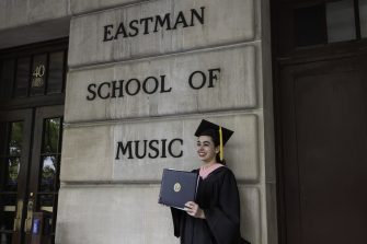 MistyLayne Drake poses with her diploma in front of Eastman School of Music