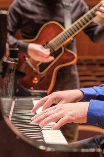 hands on guitar and piano keyboard image