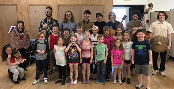 Young students from Hamlin Public School line up with seven student musicians stood behind them.