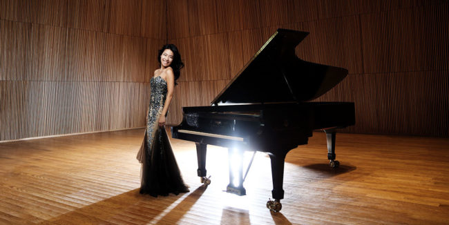 Joyce Yang standing next to piano on stage