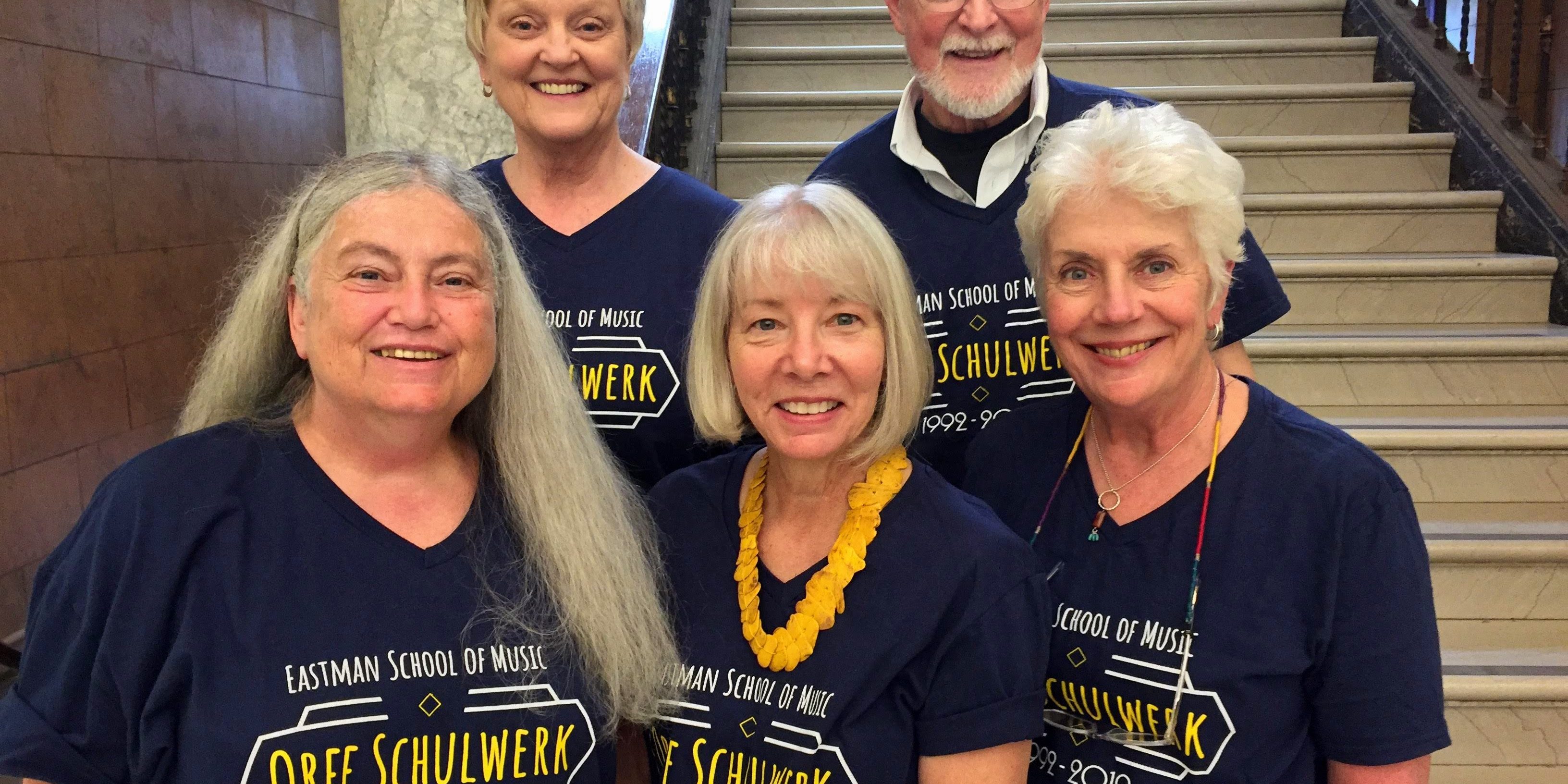 Orff faculty 2019 Five faculty members in dark blue T-shirts standing on staircase in Lowry Hall.