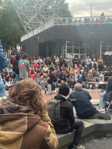 dancers perform on an outdoor stage with onlookers watching